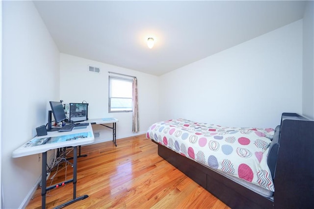 bedroom featuring visible vents, baseboards, and wood finished floors