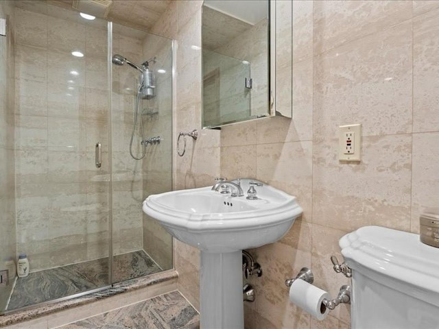 bathroom with a stall shower, toilet, and tile walls