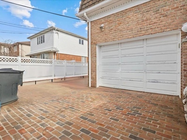 garage featuring decorative driveway and fence