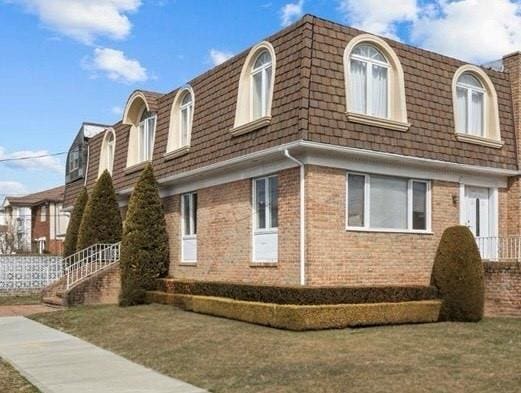 view of side of property with brick siding and mansard roof