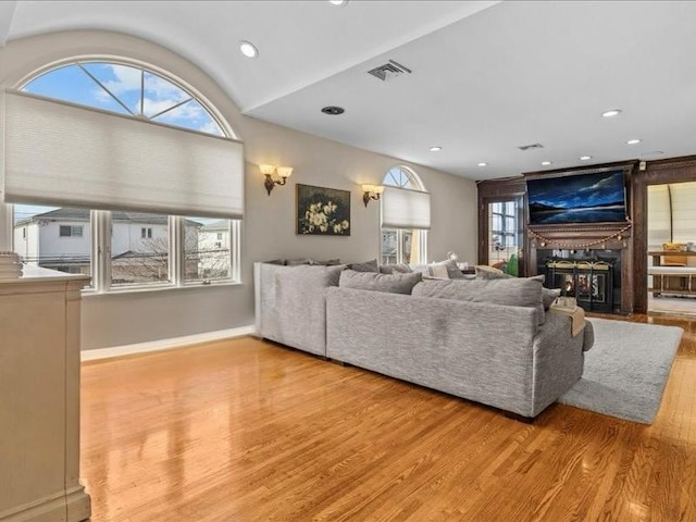 living area featuring a fireplace, wood finished floors, visible vents, and a healthy amount of sunlight