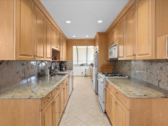 kitchen featuring a sink, light stone counters, backsplash, white appliances, and light tile patterned floors