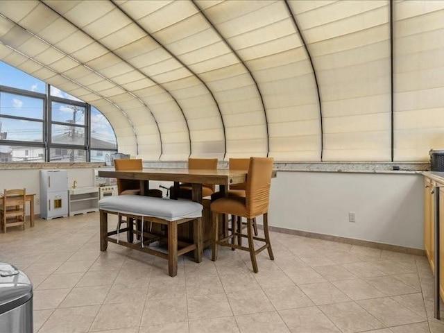 dining room featuring lofted ceiling, light tile patterned floors, and baseboards