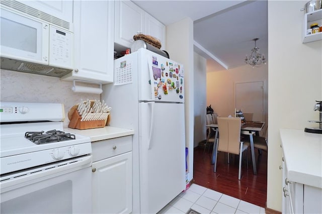 kitchen featuring a chandelier, white appliances, white cabinetry, and light countertops