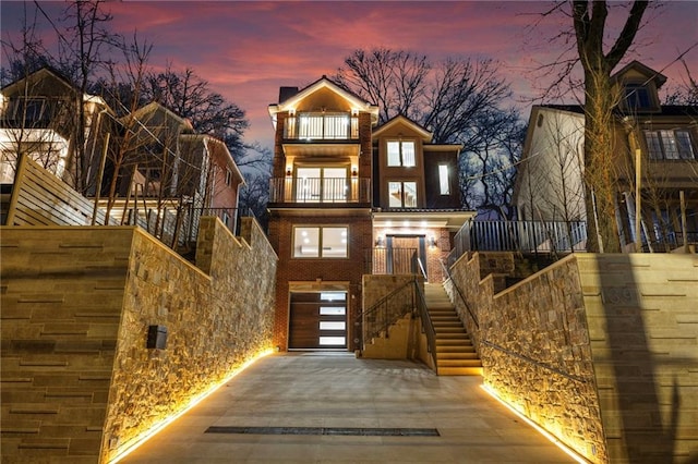 view of front of house featuring stairs, a balcony, and brick siding