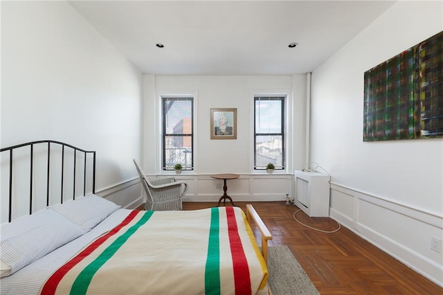 bedroom with a decorative wall, recessed lighting, and a wainscoted wall