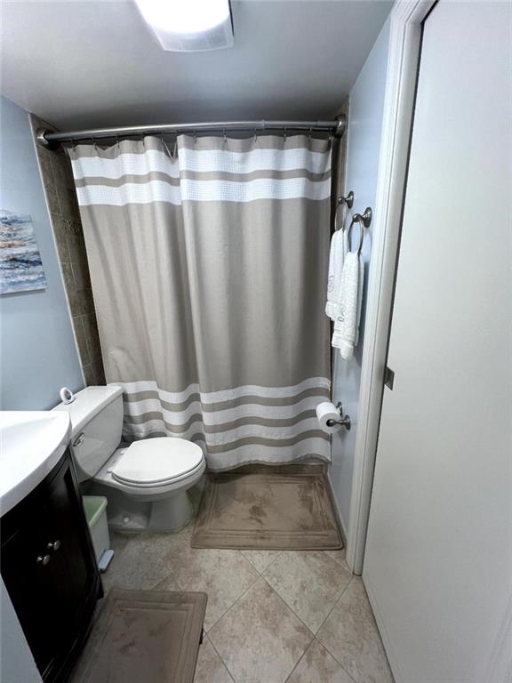 full bathroom featuring curtained shower, toilet, vanity, and tile patterned flooring