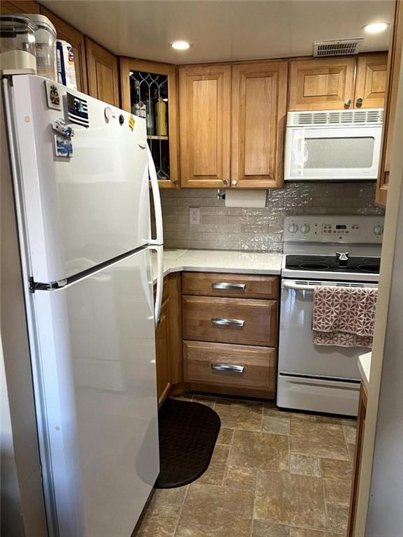 kitchen with white appliances, visible vents, brown cabinets, light countertops, and tasteful backsplash