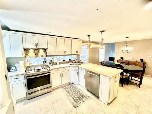 kitchen featuring light countertops, stainless steel appliances, a peninsula, backsplash, and a wall mounted AC