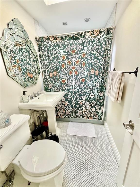 full bathroom with toilet, baseboards, and a shower with shower curtain