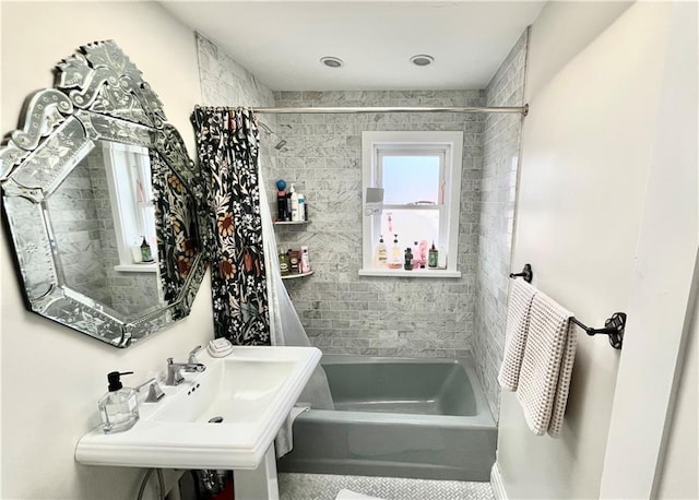 bathroom with shower / tub combo with curtain and a sink