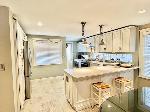 3503 Fillmore Ave, Brooklyn, NY 11234 - kitchen with stainless steel appliances, a sink, a peninsula, light countertops, and baseboards