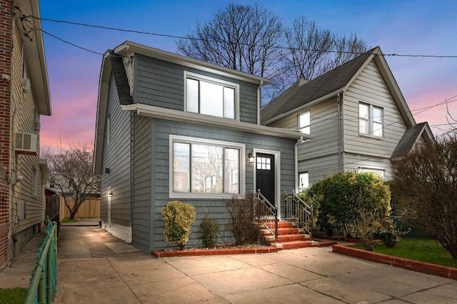 view of front of house featuring entry steps, concrete driveway, and fence