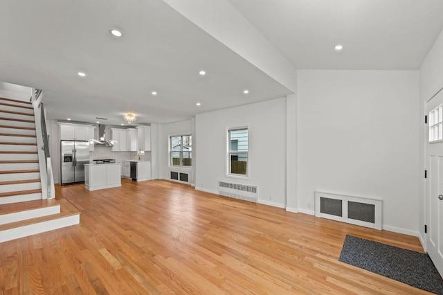 unfurnished living room featuring light wood finished floors, visible vents, radiator, stairway, and recessed lighting