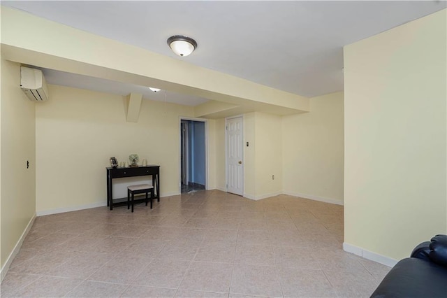 basement featuring an AC wall unit, light tile patterned flooring, and baseboards