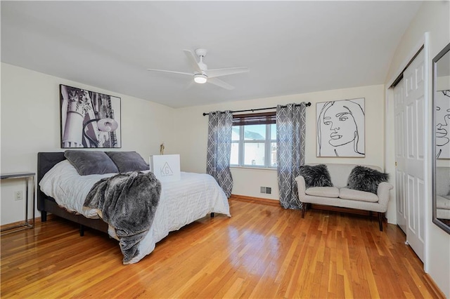 bedroom with light wood-type flooring, visible vents, a ceiling fan, a closet, and baseboards