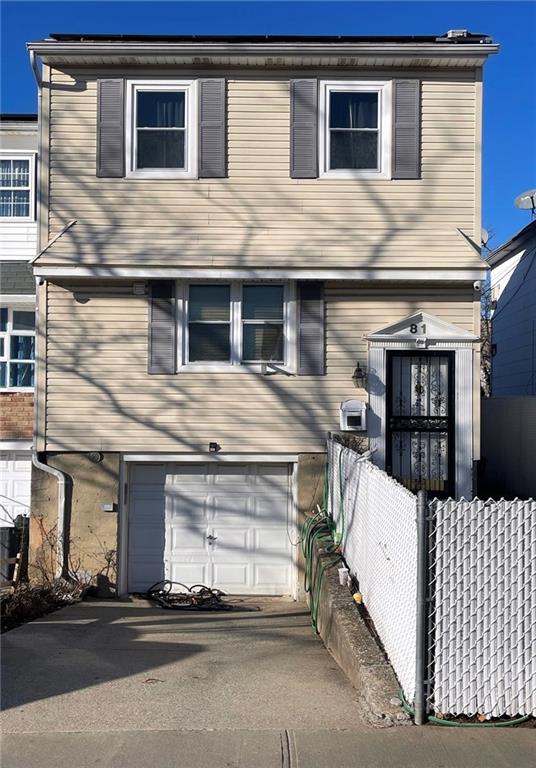 view of front of property featuring an attached garage and fence