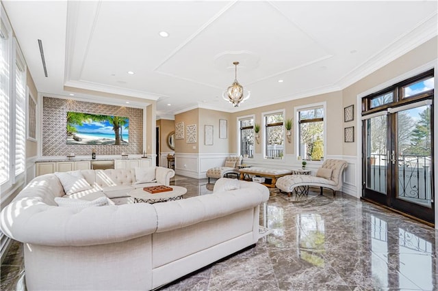 living area with a raised ceiling, a decorative wall, a wainscoted wall, and marble finish floor