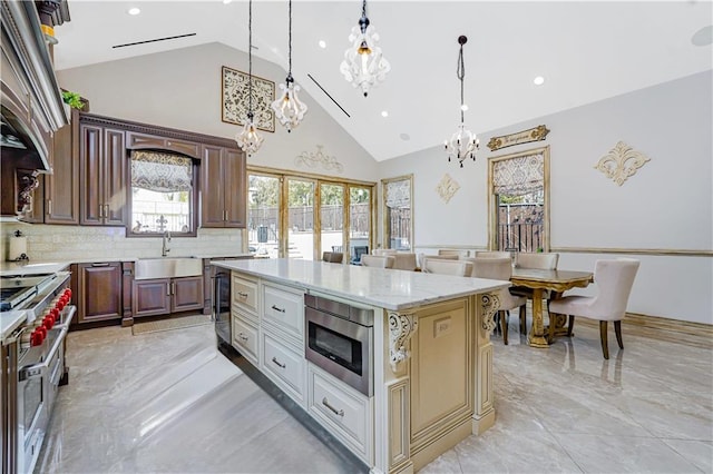 kitchen with pendant lighting, a sink, tasteful backsplash, stainless steel appliances, and light stone countertops