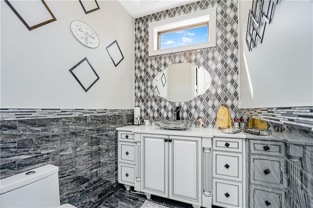 half bathroom with vanity, tile walls, and toilet