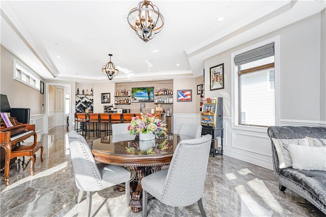 dining room with a wainscoted wall, marble finish floor, a decorative wall, a raised ceiling, and a chandelier