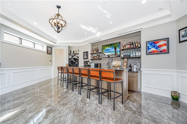 bar featuring wainscoting, wet bar, a decorative wall, marble finish floor, and a raised ceiling