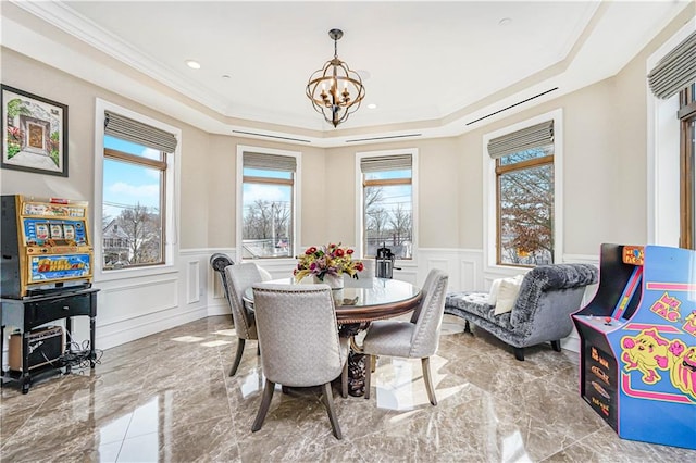 dining area with a wainscoted wall, a raised ceiling, and marble finish floor