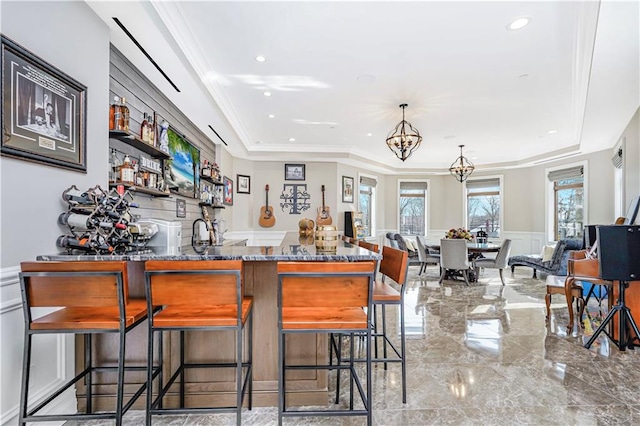 bar with ornamental molding, wainscoting, a decorative wall, a notable chandelier, and marble finish floor