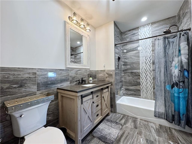 bathroom with vanity, a wainscoted wall, shower / bath combination with curtain, tile walls, and toilet