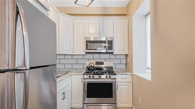 kitchen with white cabinets, light stone countertops, backsplash, and stainless steel appliances