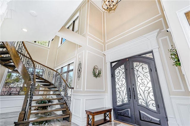 foyer with french doors, plenty of natural light, stairs, and a decorative wall