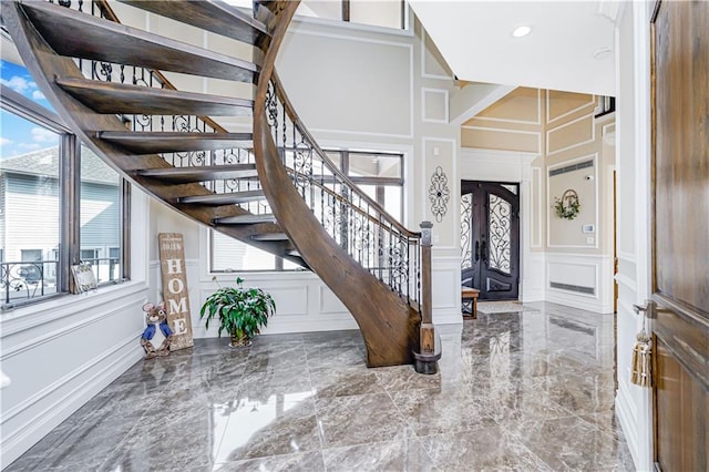 entryway featuring stairway, a decorative wall, french doors, and marble finish floor