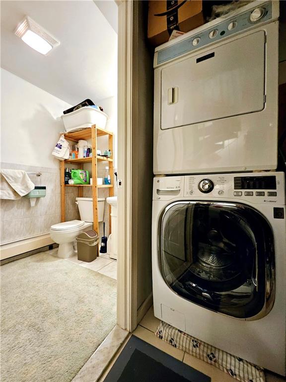 1820 73rd St Unit 1A, Brooklyn, NY 11214 - washroom with stacked washer / drying machine, a baseboard radiator, tile walls, tile patterned floors, and wainscoting