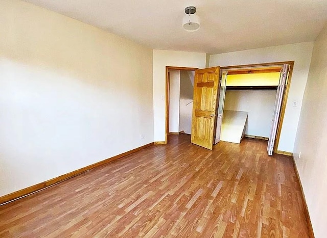 unfurnished bedroom with wood finished floors, baseboards, and a closet