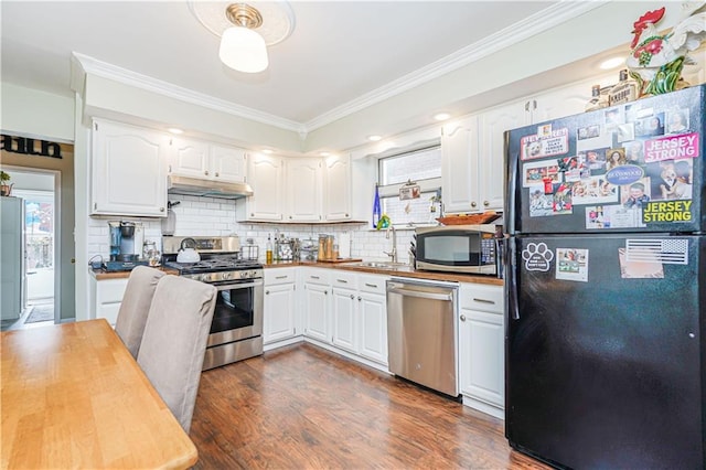 kitchen with under cabinet range hood, appliances with stainless steel finishes, dark wood-style floors, white cabinets, and a sink