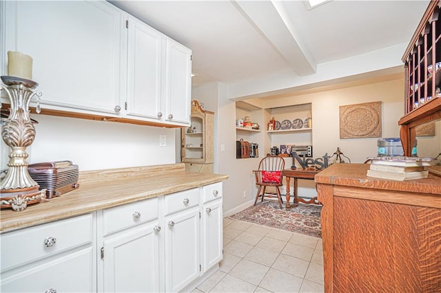 kitchen with white cabinetry, beam ceiling, light tile patterned floors, and light countertops