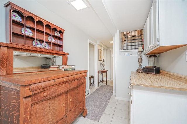 kitchen featuring light countertops, white cabinets, light tile patterned floors, and baseboards