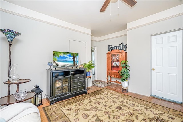 living room featuring a ceiling fan, light wood-type flooring, and ornamental molding