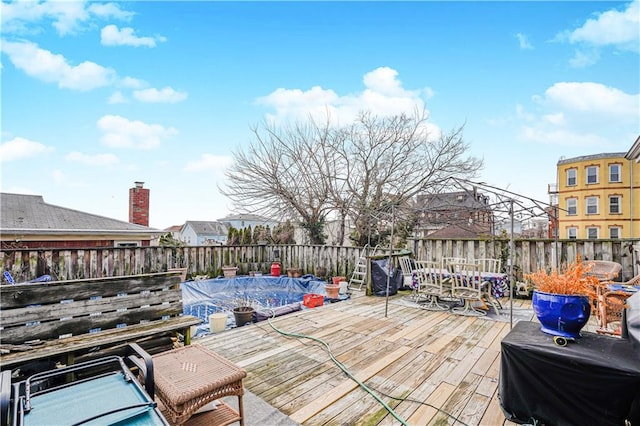 wooden deck with a fenced backyard and outdoor dining space