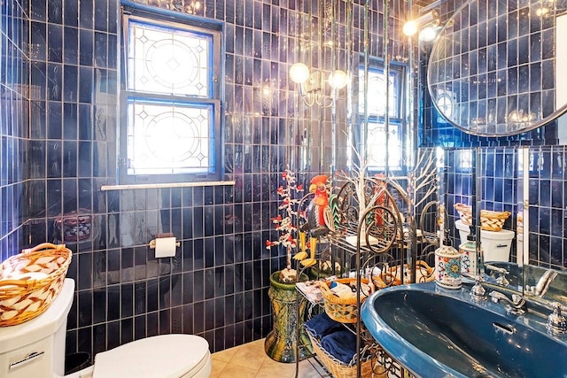 bathroom featuring tile patterned flooring, toilet, tile walls, and a sink