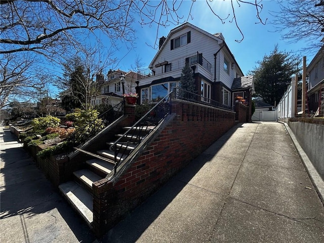 view of home's exterior featuring stairway, fence, and brick siding