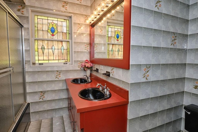 bathroom featuring a sink, an enclosed shower, and tile walls