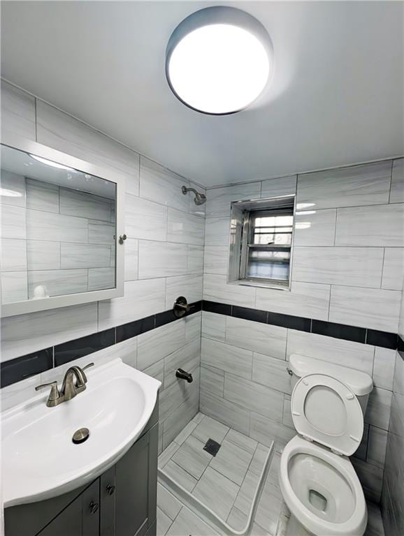 bathroom featuring vanity, tile walls, toilet, and tiled shower