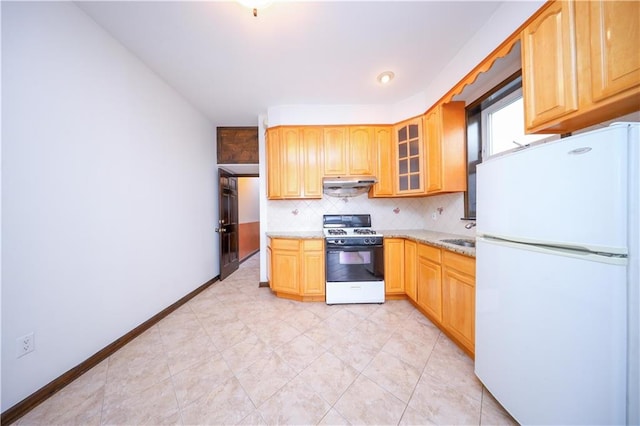 kitchen with under cabinet range hood, tasteful backsplash, freestanding refrigerator, range with gas cooktop, and glass insert cabinets