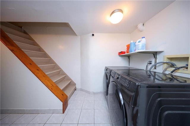 washroom with light tile patterned floors, baseboards, laundry area, and washer and clothes dryer