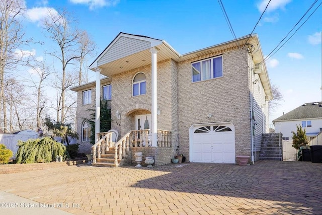 view of front of property featuring decorative driveway, brick siding, and an attached garage