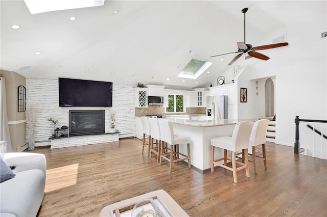 living area featuring recessed lighting, ceiling fan, wood finished floors, and vaulted ceiling with skylight