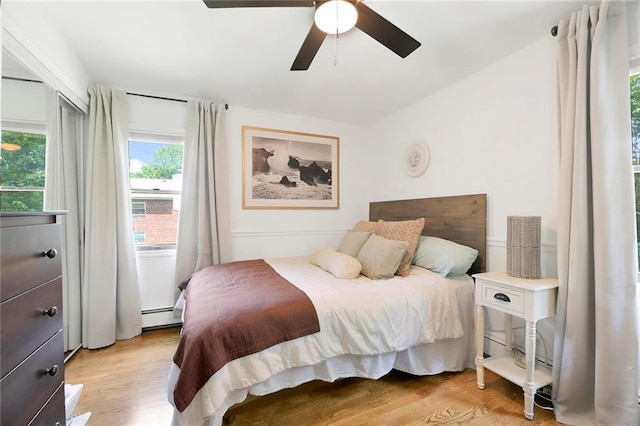 bedroom featuring light wood-type flooring, a ceiling fan, and a baseboard radiator