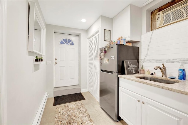 interior space featuring light tile patterned flooring, baseboards, and a sink