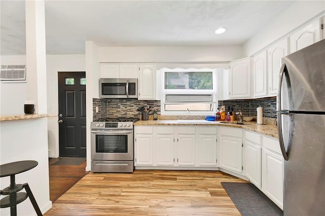 kitchen featuring light wood finished floors, white cabinetry, stainless steel appliances, and a sink